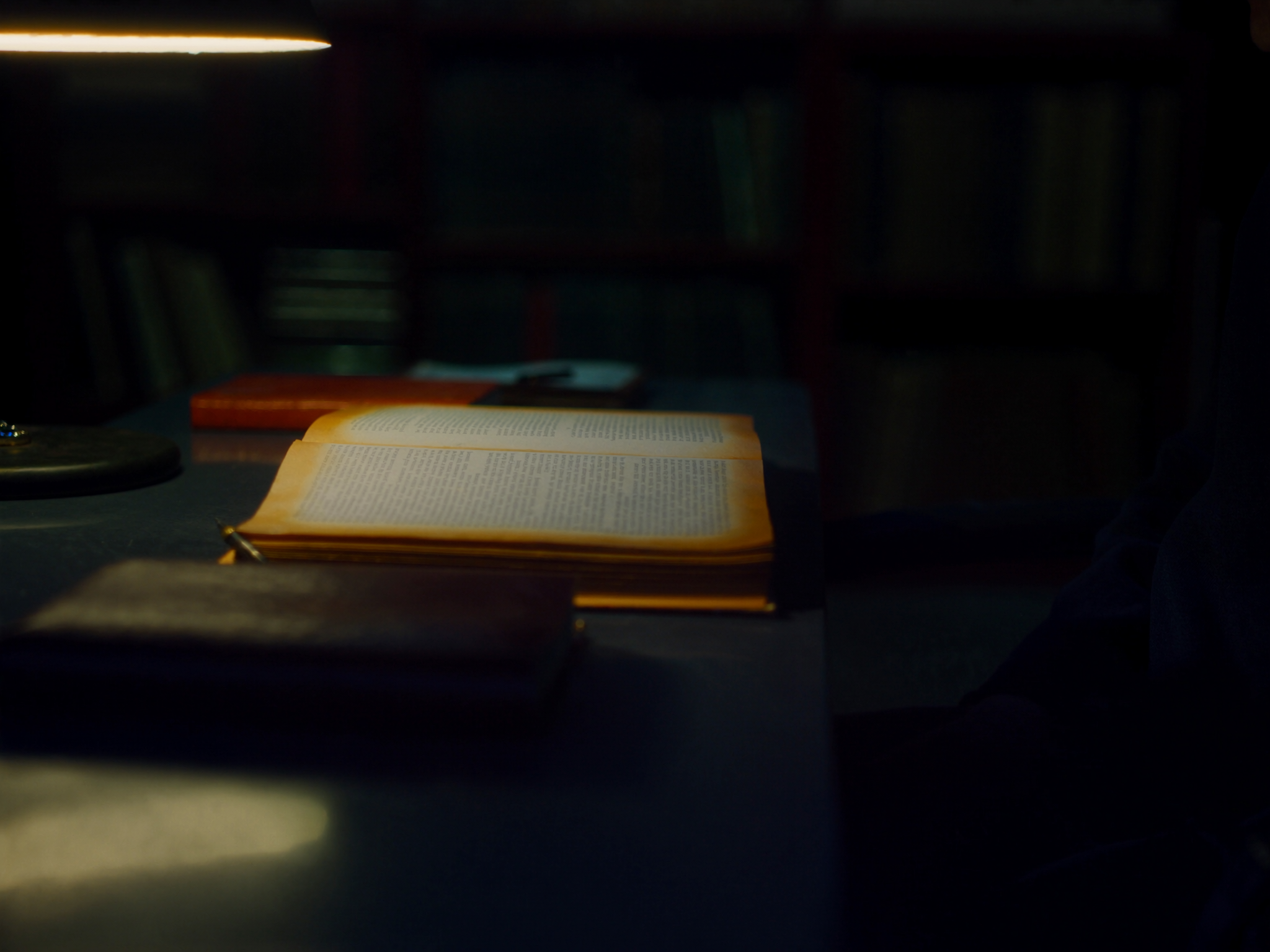 Mesa de estudo noturno com livro aberto sob luz quente: leitura como repertório acumulado