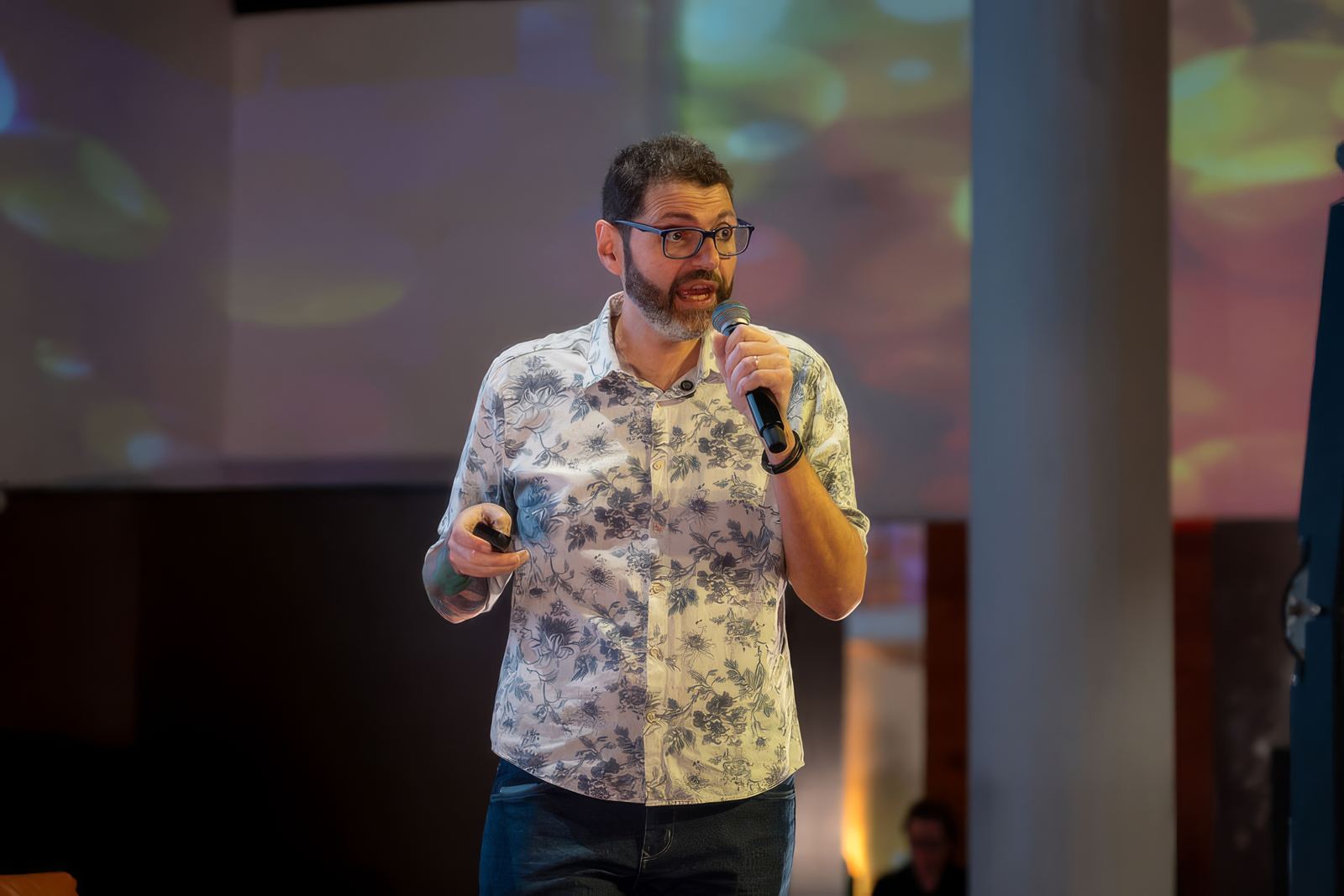 Gui Loureiro no palco, de microfone na mão, falando para a plateia