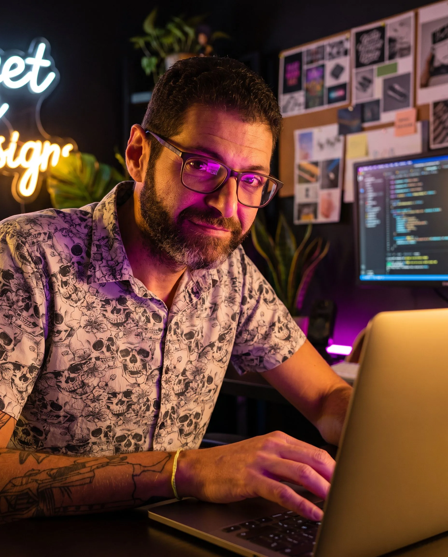 Gui Loureiro no próprio estúdio-laboratório à noite, construindo no laptop com sistemas rodando na tela