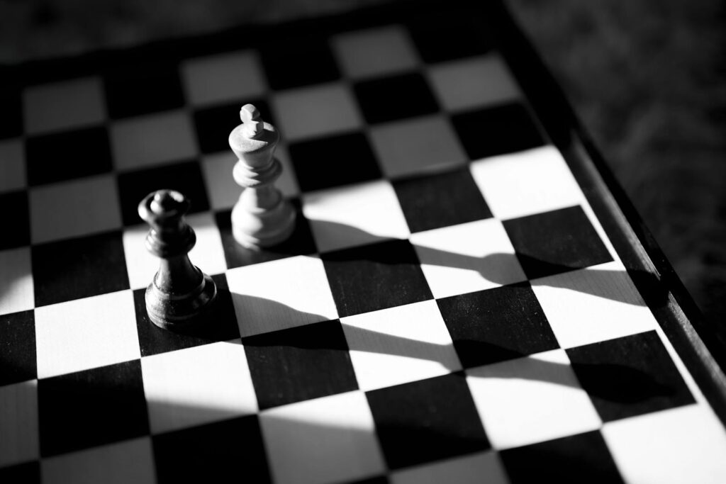 Tabuleiro de xadrez em preto e branco com sombras dramáticas · pensamento estratégico vs execução tática