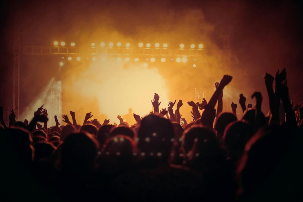 Multidão em concerto sob luzes de palco · ativação real muda comportamento, não só aparência de evento